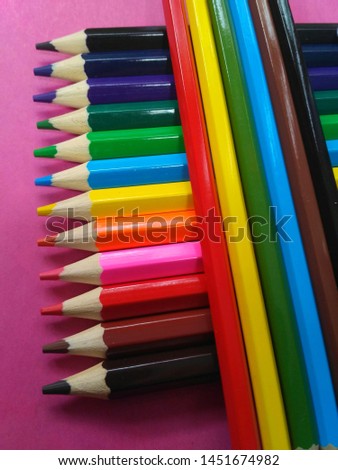 set of colored pencils on the pink table. bright saturated colors. sharpened pencil tips for drawing.