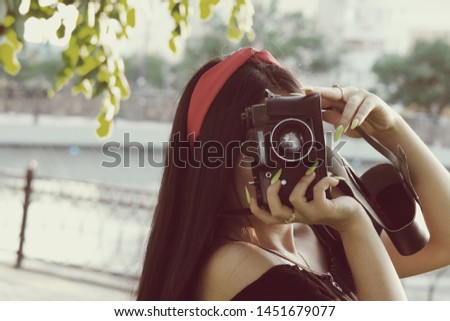 Asian Girl with camera in the park in sunset time. Brunette girl with film camera in the vintage colored image