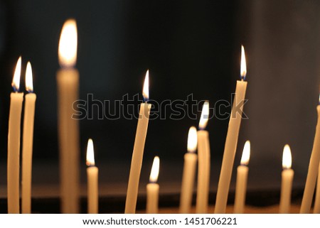 Indoor view of pattern of candles in a church. Many lights with a black background. Many vertical lighted elements. Symbol of faith and hope. Religious picture.