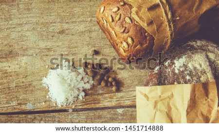 Two Loaves of Bread packed in paper on wooden table .