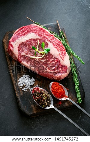 Marble raw Ribeye Steak with seasonings and red pepper on cutting Board on grey background, top view