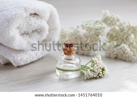 yarrow essential oil container with yarrow flowers and white towel on wooden background 