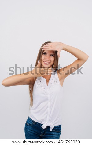 Portrait of a young stylish girl with long hair smiling, holding hands on face, looking at camera. Copy space. Isolated on white background.