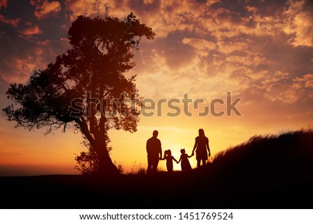 Happy family silhouette standing on against sunset time