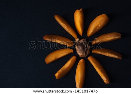 
A flower made of apricot slices and its bone on a black background.Top view.