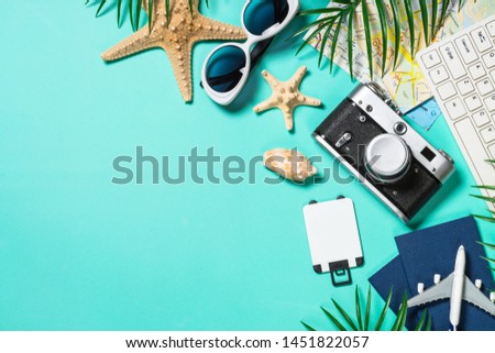 Travel concept. Summer holiday trip background. Old film camera, hat, sunglasses, starfish and palm leaves on blue background. Top view. Flat lay.