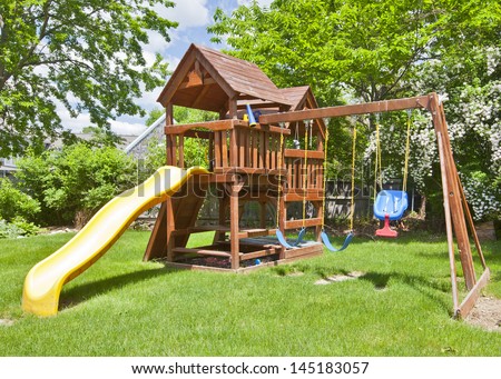 Back Yard Wooden Swing Set on Green Lawn Royalty-Free Stock Photo #145183057