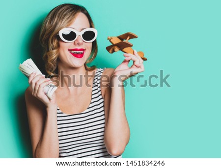 portrait of a young girl in sunglasses with money and wooden airplane on green background