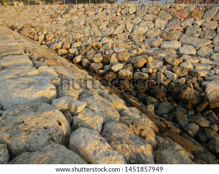Close up view of big huge stone rocks, flat lay heap pile lined row be breakwater poles long near edge coast shore beach ocean use for cut waves. Safe concept stony surround dock, port, lagoon, pier
