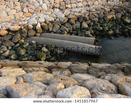 Close up view of big huge stone rocks, flat lay heap pile lined row be breakwater poles long near edge coast shore beach ocean use for cut waves. Safe concept stony surround dock, port, lagoon, pier
