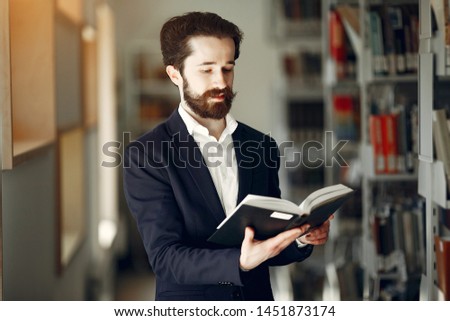 Man in a library. Guy in a black suit. Student with a books.