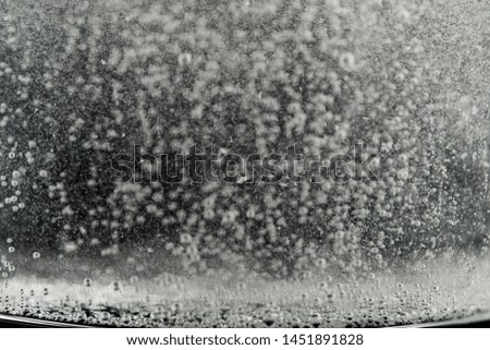 White medication tablet dissolving in a glass filled with water, bubbles are seen and the remains of the tablet dissolving. Act on a black background.