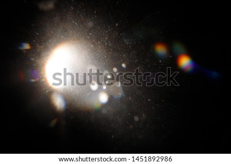 Lens Flare. Light over black background. Easy to add overlay or screen filter over photos. Abstract sun burst with digital lens flare background. Gleams rounded and hexagonal shapes, rainbow halo. Royalty-Free Stock Photo #1451892986