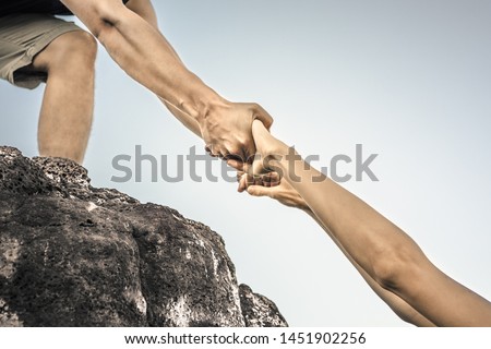 Giving a helping hand up a mountain. Helping someone in need concept.  Royalty-Free Stock Photo #1451902256