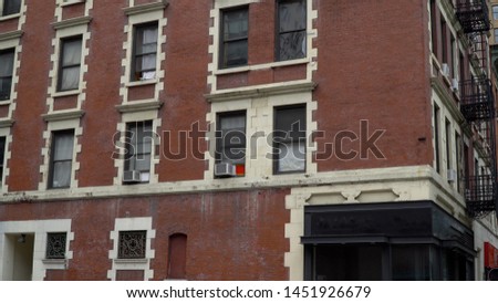 Typical New York City style brick apartment building day establishing shot on street corner with rent control loft above generic bar restaurant location with blank signage for digital edit space dx