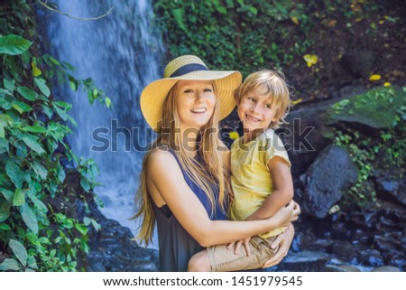 Mom and son tourists on the background of a waterfall. Traveling with kids concept. What to do with children Children friendly place