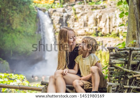 Mom and son tourists on the background of a waterfall. Traveling with kids concept. What to do with children Children friendly place