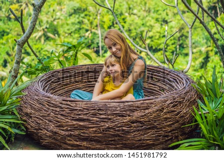 Bali trend, straw nests everywhere. Happy family enjoying their travel around Bali island, Indonesia. Making a stop on a beautiful hill. Photo in a straw nest, natural environment. Lifestyle