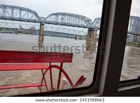 View of the Purple People Bridge in Cincinnati, Ohio and the paddle wheel of a river boat from the boat's window.