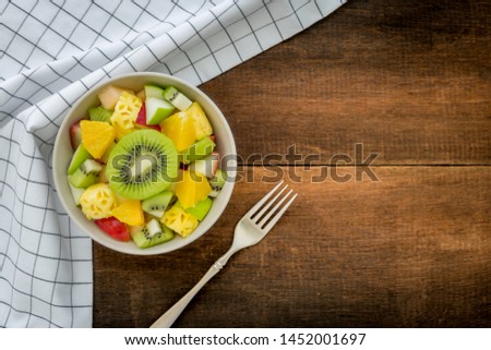 Fruit salad in white bowl on wooden background.