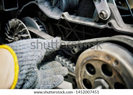mechanic check the condition of old motorcycle or big scooter drive belt .Check the belt tension at garage.motorcycle repair, maintenance and service concept                           Royalty-Free Stock Photo #1452007451