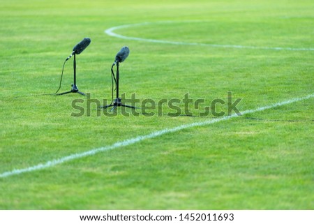 Professional furry microphone on green grass on a soccer field