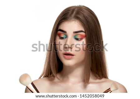 Closeup portrait of beautiful young woman with brushes for make-up. Isolated over white background.