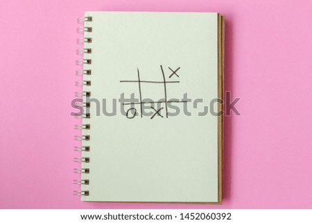 Drawing heart in tic tac toe on paper,xo game, on pink background.