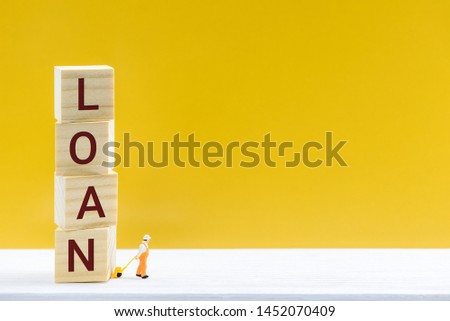 Personal loan / payday loan concept : Miniature worker uses a hand-pull pallet drags square cubes with words LOAN, depicts a sum of long-term money borrowed and expected to be paid back with interest Royalty-Free Stock Photo #1452070409