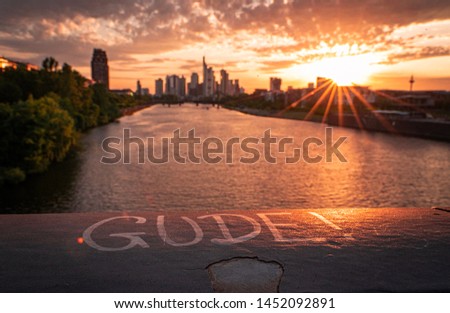 Gude means hello in front of the skyline of Frankfurt by sunset