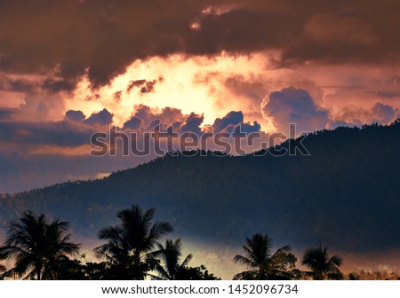 Thunderstorm and lightning over mountain and palm trees on a tropical island	
