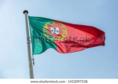 Portugal flag, Portuguese national symbol waving against clear blue sky, sunny day