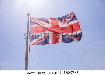 United Kingdom flag, Great Britain national symbol waving against clear blue sky, sunny day