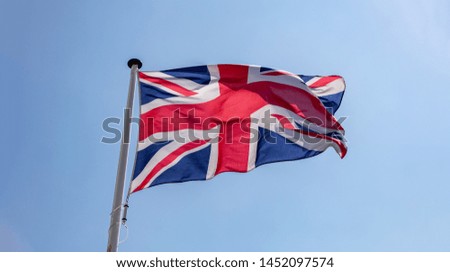 United Kingdom flag, Great Britain national symbol waving against clear blue sky, sunny day