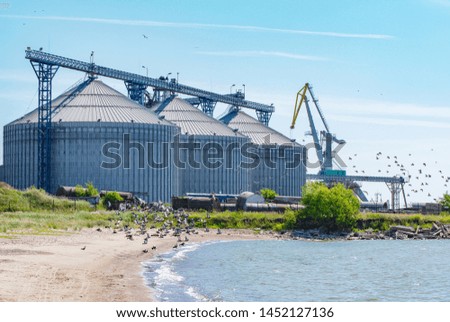 Large grain elevator silos in port with flying birds and sea coast (Port of Liepaja, Latvia)