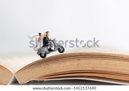 Miniature people : Couple riding the motorcycle on old book  , Valentine's Day concept