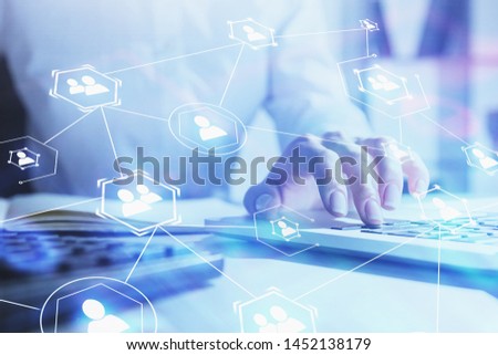 Hand of businesswoman typing on laptop in blurred office with double exposure of social network icons. Concept of human relations and hi tech. Toned image