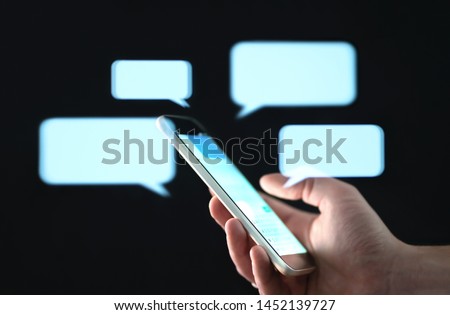 Text messages in cellphone screen with abstract hologram speech bubbles. Instant messaging app. Texting, group chat, sexting or sms concept. Customer service help desk with live support chatbot. Royalty-Free Stock Photo #1452139727