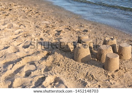 View of beach with little sand figures near sea on sunny summer day. Space for text