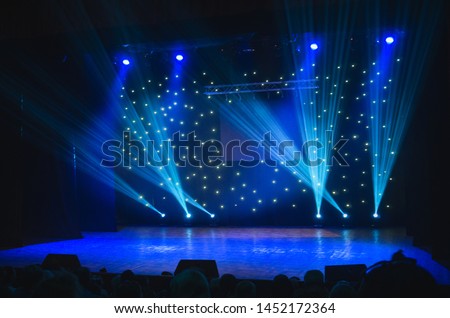 Blurred show backdrop. Sparkling stage lights. Several projectors in the dark. Blue light beams spotlights on stage at time of entertainment show. Laser and lights show. Small depth of view Royalty-Free Stock Photo #1452172364