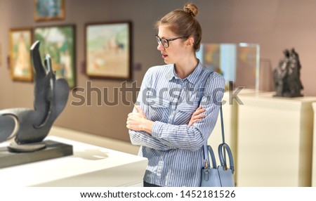 woman visitor in historical museum looking at art object