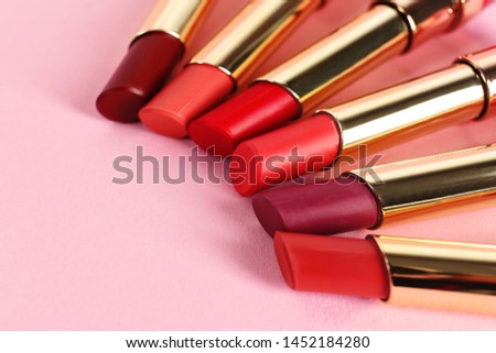 Set of bright lipsticks in gold tubes on pink background, space for text