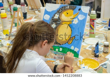 The girl draws a hedgehog. Creative teen girl paitning a picture on easel. Interior of the art school for drawing children. Creativity and people concept