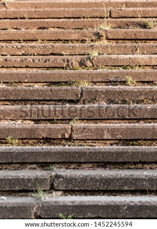 Concrete staircase overgrown with grass, without railing. Old outdoor stone steps.