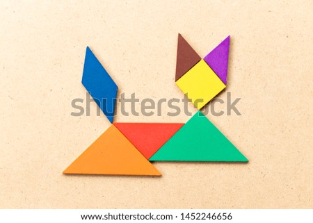 Color tangram puzzle in lying down cat shape on wood background