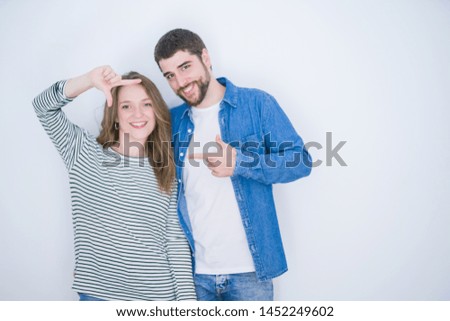 Young beautiful couple standing together over white isolated background smiling making frame with hands and fingers with happy face. Creativity and photography concept.