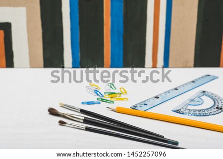 Brushes and stationery near abstract painting