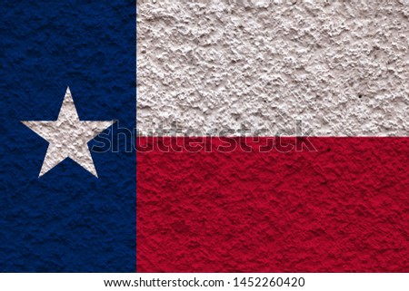 The national flag of the US state Texas in against a gray wall with stony surface on the day of independence in colors of blue red and white. Political and religious disputes, customs and delivery