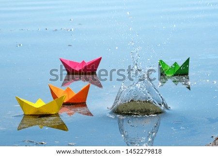 Colorful paper boats in the spring river. The result of a successful business. Origami toys for children.