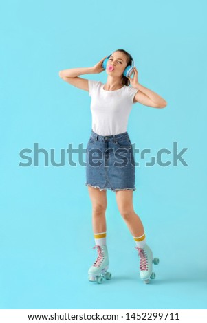 Beautiful young girl on roller skates listening to music against color background